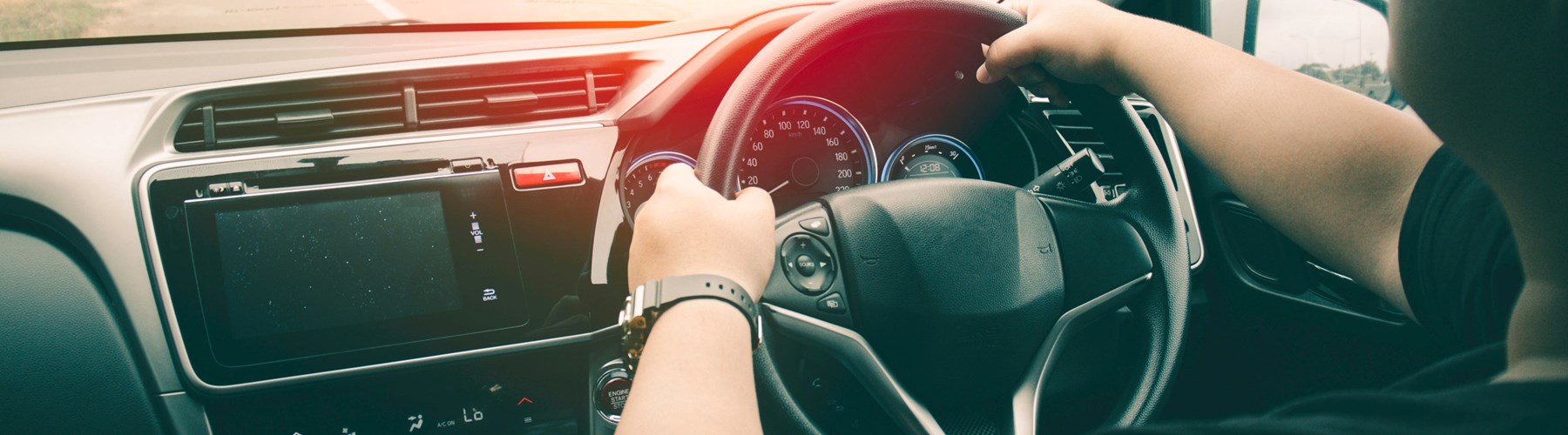 close up of hands on steering wheel and dashboard