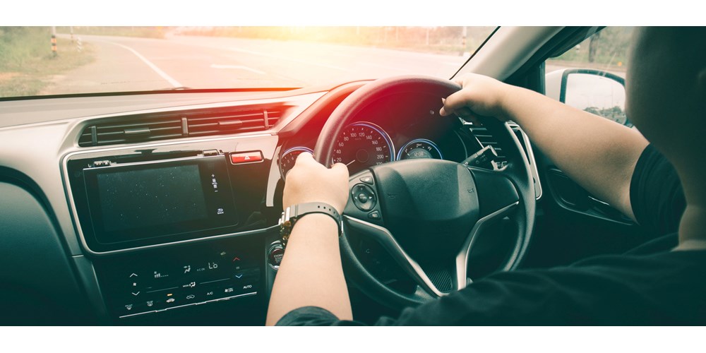 close up of hands on steering wheel and dashboard